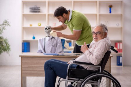 Téléchargez les photos : Vieux patient masculin en fauteuil roulant visitant squelette médecin - en image libre de droit