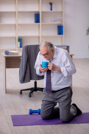 Foto de Viejo empleado haciendo ejercicios deportivos durante el descanso - Imagen libre de derechos