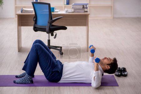 Foto de Joven empleado haciendo ejercicios deportivos durante el descanso - Imagen libre de derechos