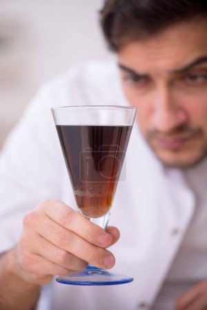 Téléchargez les photos : Jeune chimiste examinant les boissons gazeuses au laboratoire - en image libre de droit