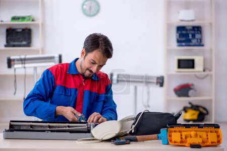 Photo for Young repairman repairing air-conditioner at workshop - Royalty Free Image