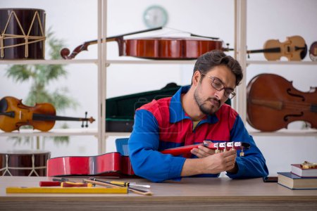 Foto de Joven reparando instrumentos musicales en interiores - Imagen libre de derechos