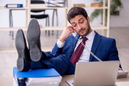 Téléchargez les photos : Young businessman employee speaking by phone at workplace - en image libre de droit