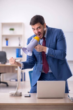 Photo for Young employee holding megaphone in the office - Royalty Free Image