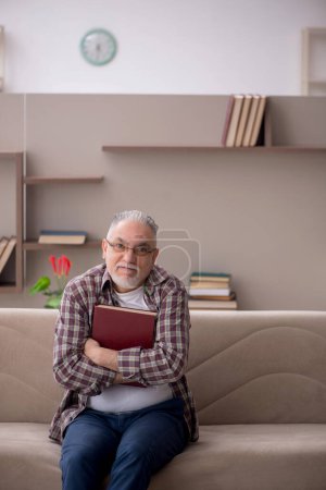 Téléchargez les photos : Old man reading book at home during pandemic - en image libre de droit