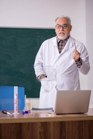 Photo for Old teacher chemist sitting in the classroom - Royalty Free Image
