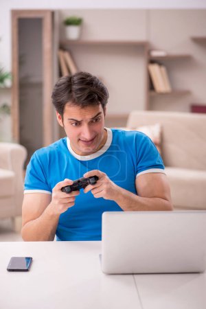 Foto de Joven estudiante masculino jugando videojuegos en casa - Imagen libre de derechos