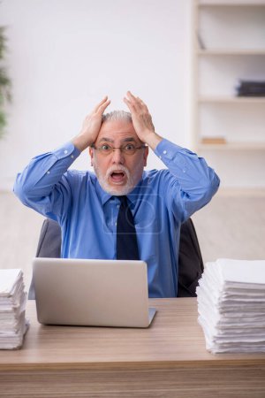 Téléchargez les photos : Old employee and too much work at workplace - en image libre de droit