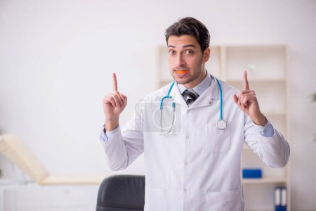 Téléchargez les photos : Young doctor wearing mouthguard in the clinic - en image libre de droit