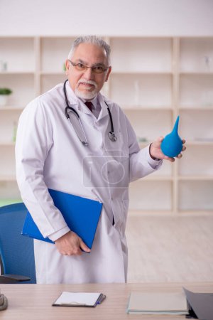 Téléchargez les photos : Old doctor gastroenterologist holding enema - en image libre de droit