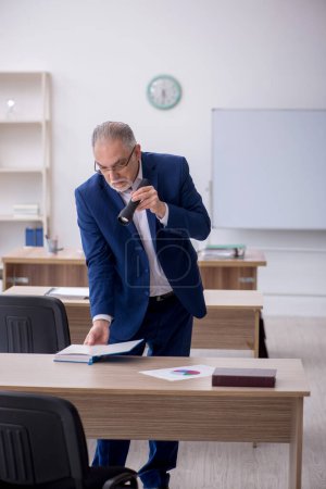 Téléchargez les photos : Old teacher holding penlight in the classroom - en image libre de droit