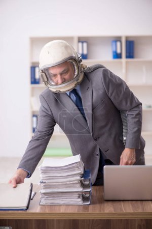 Foto de Old employee wearing spacesuit in the office - Imagen libre de derechos