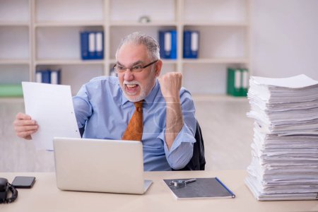 Téléchargez les photos : Old male employee and too much work at workplace - en image libre de droit