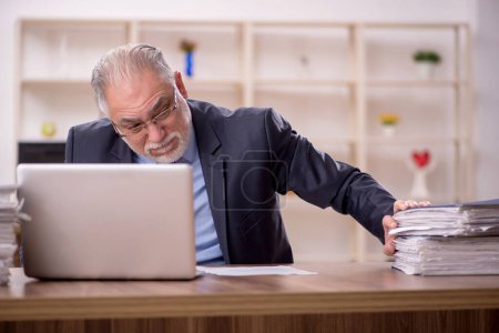 Foto de Viejo empleado de negocios descontento con el trabajo excesivo en la oficina - Imagen libre de derechos
