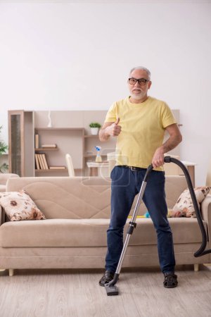Téléchargez les photos : Le vieil homme nettoie la maison - en image libre de droit