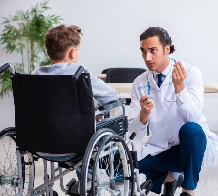 Foto de El joven doctor pediatra y niño en silla de ruedas - Imagen libre de derechos