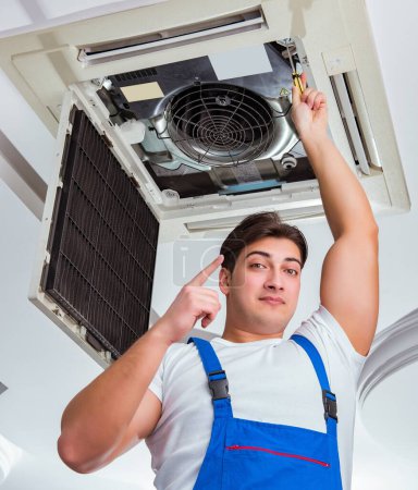 Téléchargez les photos : Le travailleur réparer l'unité de climatisation de plafond - en image libre de droit