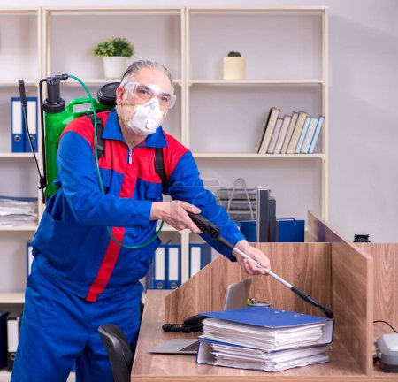 Foto de El viejo contratista profesional haciendo control de plagas en la oficina - Imagen libre de derechos