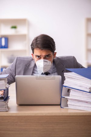 Téléchargez les photos : Jeune homme d'affaires travaillant sur le lieu de travail pendant la pandémie - en image libre de droit