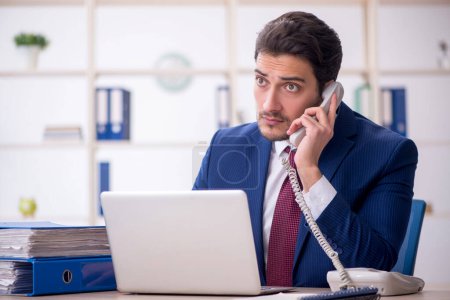 Téléchargez les photos : Young businessman employee speaking by phone at workplace - en image libre de droit