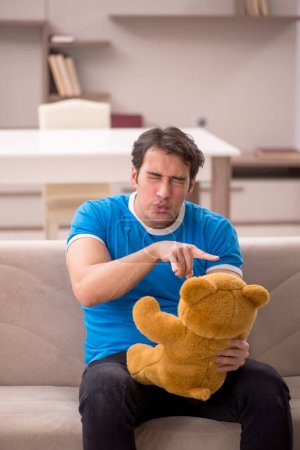 Photo for Young man sitting with bear toy at home - Royalty Free Image