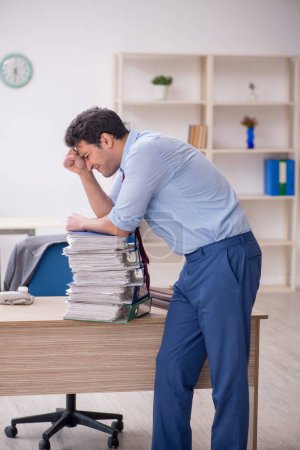 Téléchargez les photos : Young employee unhappy with excessive work at workplace - en image libre de droit