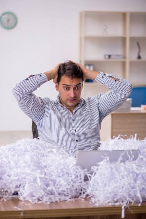 Photo for Young businessman employee and a lot of cut papers at workplace - Royalty Free Image