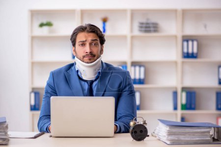 Téléchargez les photos : Jeune homme d'affaires employé après un accident assis sur le lieu de travail - en image libre de droit