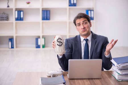 Photo for Young employee holding moneybag at workplace - Royalty Free Image