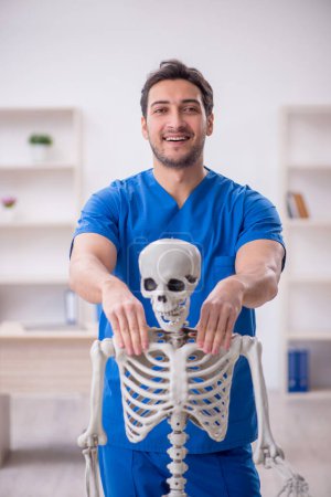 Foto de Joven doctor y paciente esqueleto en la clínica - Imagen libre de derechos