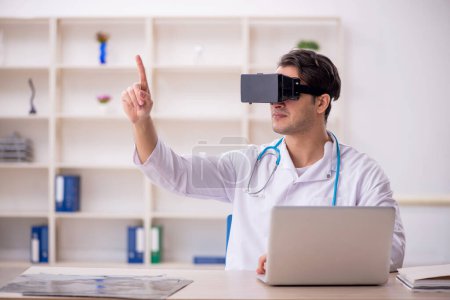 Téléchargez les photos : Jeune médecin jouissant de lunettes virtuelles à la clinique - en image libre de droit