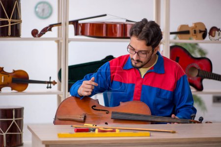 Téléchargez les photos : Jeune homme réparant des instruments de musique à l'intérieur - en image libre de droit