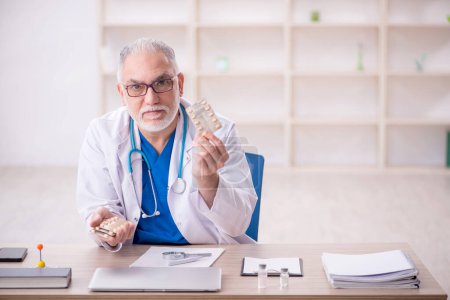 Téléchargez les photos : Vieux médecin suggérant des pilules à la clinique - en image libre de droit