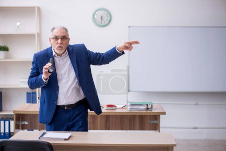 Photo for Old teacher holding penlight in the classroom - Royalty Free Image