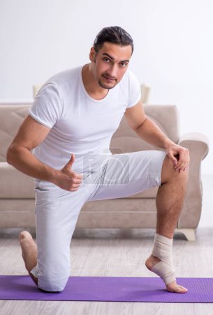 Foto de El hombre lesionado pierna haciendo ejercicios en casa - Imagen libre de derechos