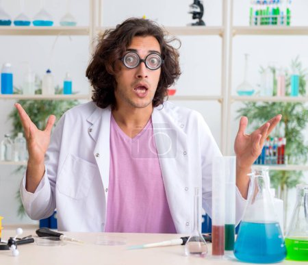 Foto de El gracioso químico masculino que trabaja en el laboratorio - Imagen libre de derechos