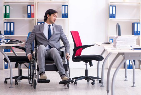 Téléchargez les photos : Le jeune et beau employé en fauteuil roulant travaillant dans le bureau - en image libre de droit