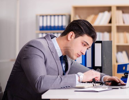 Téléchargez les photos : L'homme d'affaires fatigué qui travaille dans le bureau - en image libre de droit