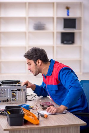 Téléchargez les photos : Jeune réparateur réparer l'ordinateur à l'atelier - en image libre de droit