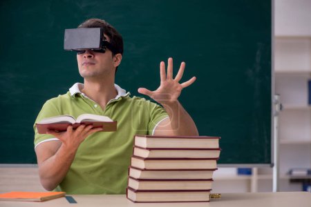 Téléchargez les photos : Jeune étudiant portant des lunettes virtuelles en classe - en image libre de droit