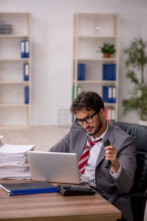 Téléchargez les photos : Jeune homme d'affaires employé mécontent du travail excessif au bureau - en image libre de droit