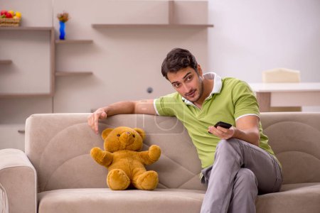 Photo for Young male student with toy bear at home - Royalty Free Image