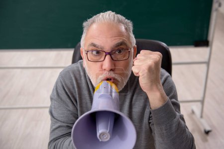 Téléchargez les photos : Old teacher holding megaphone in the classroom - en image libre de droit