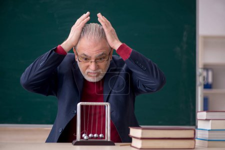 Téléchargez les photos : Vieux professeur physicien assis dans la salle de classe - en image libre de droit