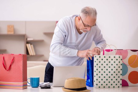 Foto de Old man with many bags in Christmas concept indoors - Imagen libre de derechos