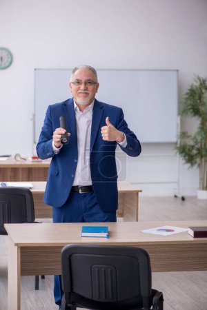 Photo for Old teacher holding penlight in the classroom - Royalty Free Image