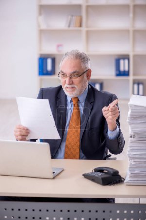Photo for Old male employee and too much work at workplace - Royalty Free Image