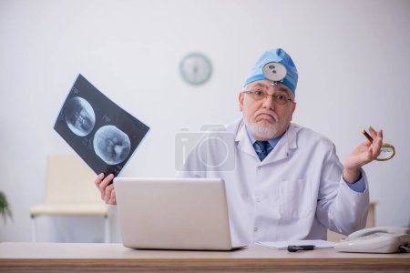 Téléchargez les photos : Old docror otolaryngologist working at the hospital - en image libre de droit