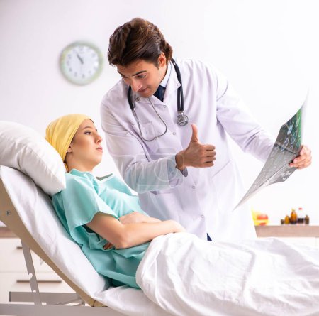 Téléchargez les photos : Le jeune beau médecin visitant une patiente en oncologie - en image libre de droit
