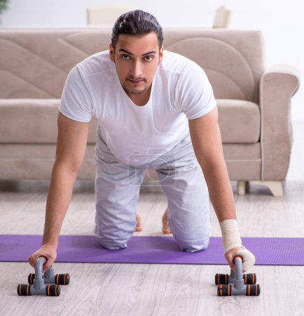 Photo for The hand injured man doing exercises at home - Royalty Free Image